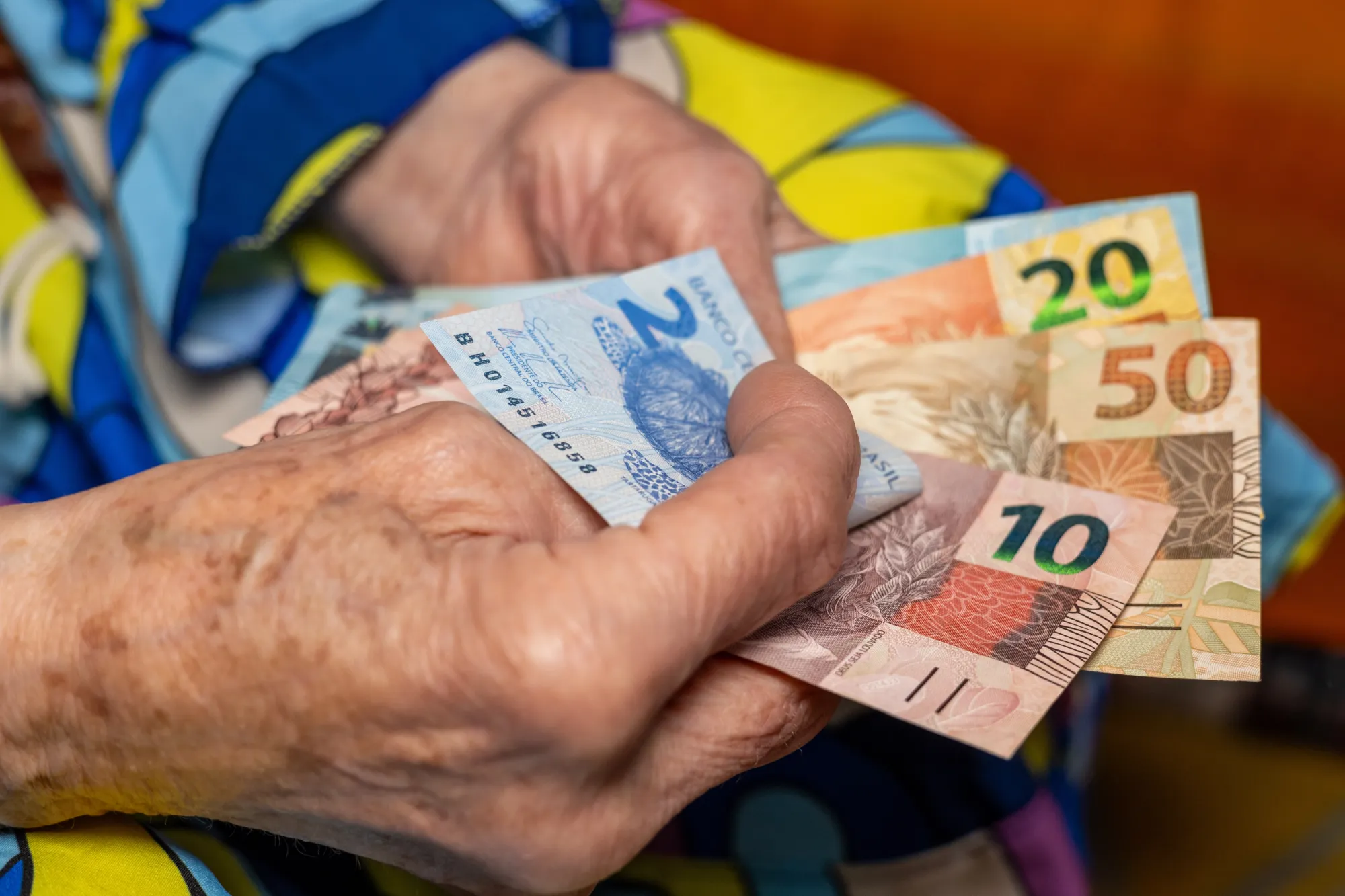 Pessoa idosa contando dinheiro recebido pelo BPC, o benefício de prestação continuada oferecido pela assistência social brasileira conforme a LOAS